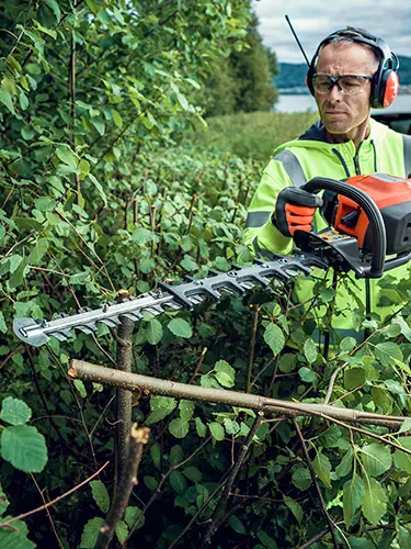 Eine Hecke wird mit einer Husqvarna Heckenschere geschnitten
